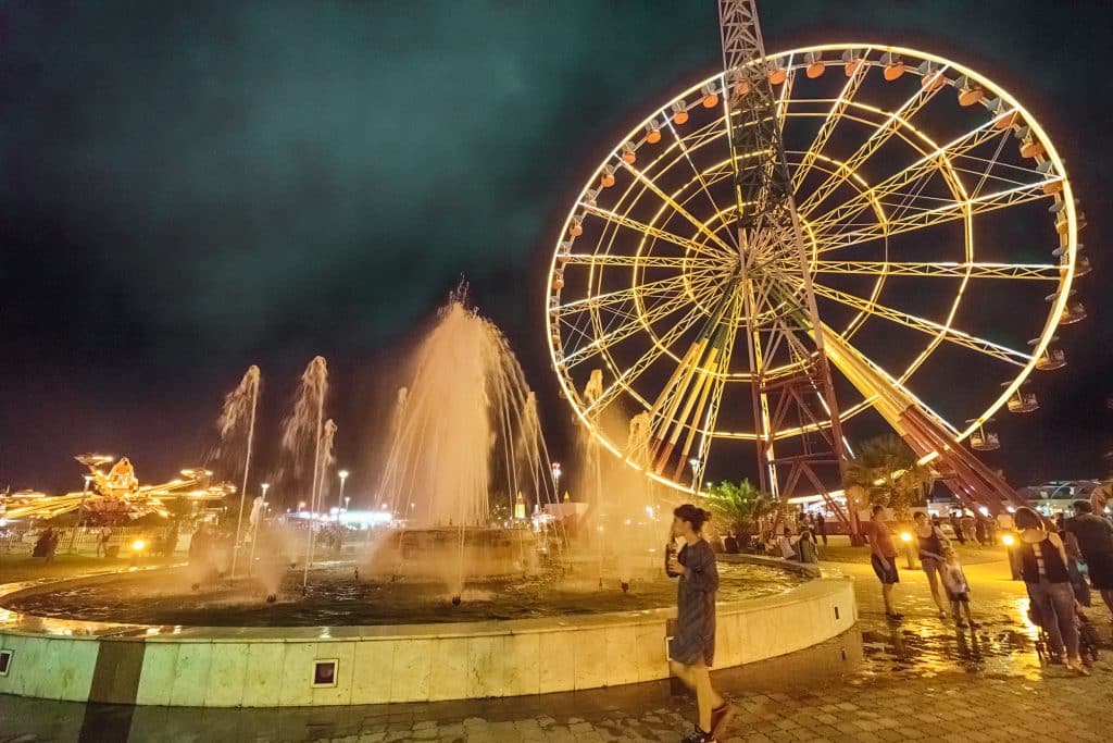 В центре парка развлечений фонтан и обзорное колесо